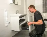Hantverkare installerar ett nytt badrumsskåp som en del av en totalrenovering badrum.