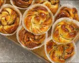 Nybakade bullar med mandelmassa, kanel och vallmofrön i pappersformar på en träbricka.