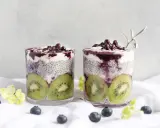 Två glas med chia pudding recept, fyllda med kiwi, yoghurt och blåbär. En vacker och hälsosam frukost.