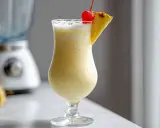 En krämig pina colada med ananasskiva och körsbär, redo att avnjutas.