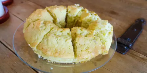 En saftig sockerkaka, uppskuren i bitar på ett fat, ligger på ett rustikt träbord.