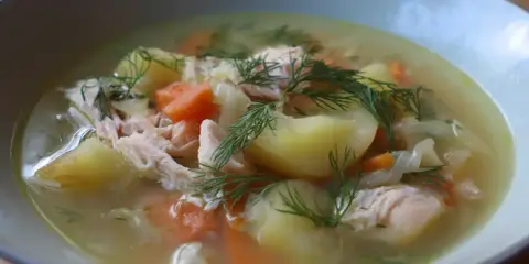 En närbild av en skål med värmande fisksoppa, full av potatis, morötter och dill. Ett perfekt fisksoppa recept för en kall dag.