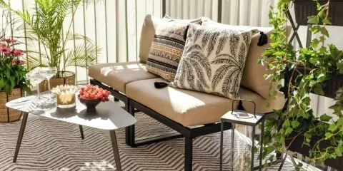 Mysig uteplats med soffa, kuddar, bord med vindruvor och växter. Perfekt för att styla uteplatsen.
