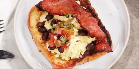 En tallrik med fattiga riddare toppad med äggröra, svarta bönor och salsa.