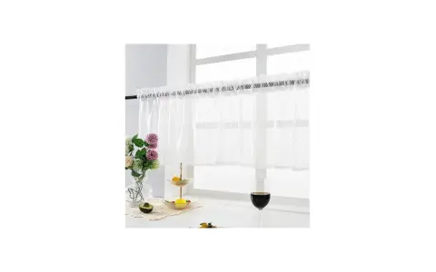 Vit gardinkappa och längder med spetskant hänger för ett fönster. Blommor, frukt och ett glas vin på fönsterbrädan.