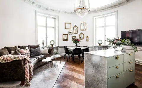 Ett vardagsrum med mörk soffa, marmorö, och en matplats. Massor av speglar på väggen ger inredning inspiration.