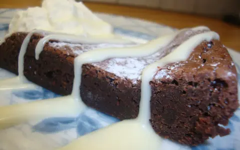 En bit chokladkaka med vispad grädde och vit chokladsås. En härlig vit kladdkaka som smälter i munnen.