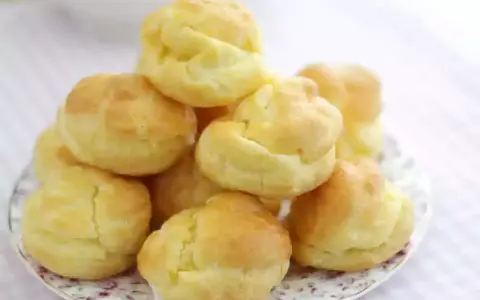En hög med gyllene petit choux på en vacker tallrik, redo att fyllas med grädde eller glass.
