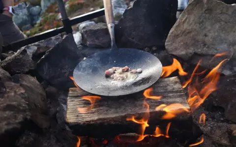 Stekt fläsk på en stekpanna över öppen eld, en del av ett kolbulle recept.