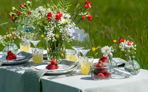 Vackert dukat bord med blommor och jordgubbar för att duka till midsommar.
