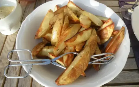 En skål med gyllene klyftpotatis i ugn, redo att serveras med en sallad och dipp. Perfekt tillbehör!