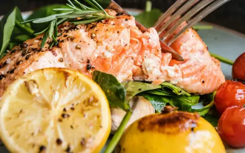 Saftig lax med citron och rosmarin, perfekt för ett enkelt lax recept. Serveras med körsbärstomater och gröna blad.