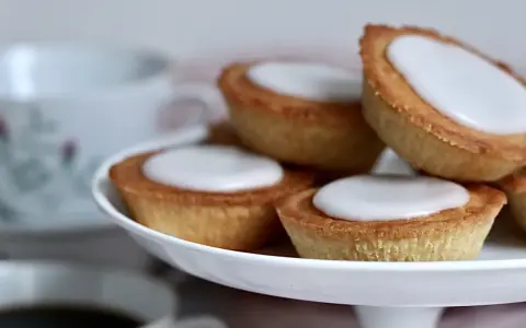 Små, gyllene mazariner med vit glasyr på ett fat. Perfekt för fikastunden, här är ett enkelt mazariner recept.