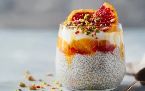En läcker chiapudding med kvarg, apelsin och blodapelsin, toppad med pistagenötter.