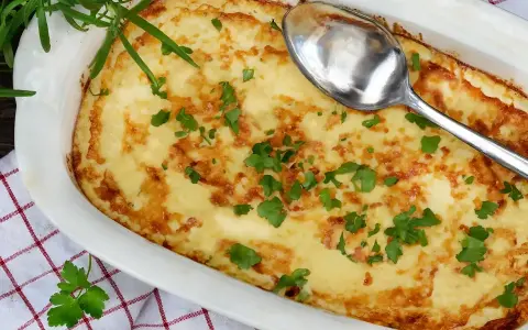 En gyllene omelett i ugn, toppad med färsk persilja och en sked redo att servera. Perfekt för en mysig frukost eller lätt lunch.