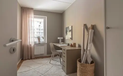 Ett mysigt hemmakontor med skrivbord, stol, en stor matta och rullar med tyg.