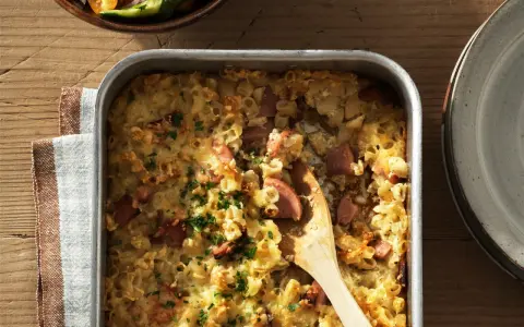 En gyllene makaronilåda med korv, toppad med persilja, redo att serveras. En klassisk svensk rätt som värmer själen.