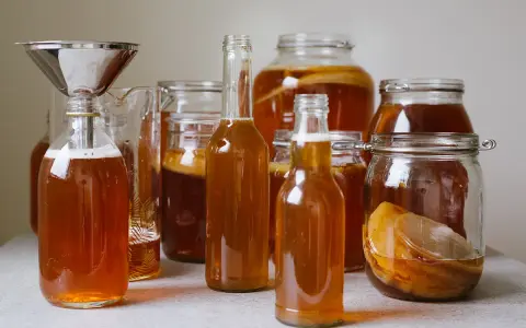 Flera flaskor och burkar med hemgjord kombucha, redo för andra jäsningen. Ett perfekt kombucha recept för hemmabruk.