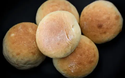 Fem nybakade frallor på en svart bakgrund. Perfekt för ett enkelt frallor recept.