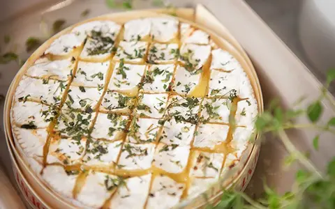 En härlig brie i ugn, gyllene och bubblande, toppad med örter. Perfekt för att doppa bröd i.