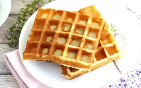 Två gyllene frasvåfflor på en tallrik, redo att avnjutas. Ett perfekt recept för frukost eller fika.