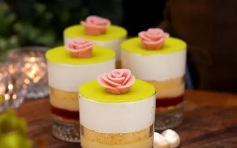 Fyra små prinsesstårta i glas, dekorerade med rosa marsipanrosor och gul marsipanlock. En festlig dessert.