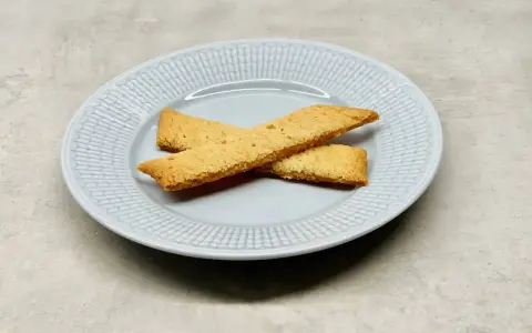 Två gyllene kolasnittar ligger korslagda på en ljusblå tallrik. Perfekt för ett enkelt kolasnittar recept.