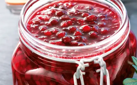 En burk med hemlagad lingonsylt, perfekt för ditt lingonsylt recept. Bären glänser i den söta lagen.