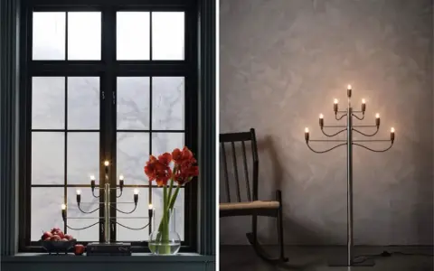 Två fina adventsljusstakar, en i ett mörkt fönster med amaryllis och äpplen, en annan som golvlampa bredvid en gungstol.