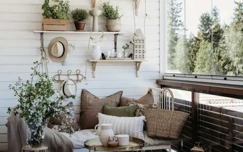 Mysig balkongdesign med kuddar, växter och en korgväska. En perfekt plats för avkoppling.