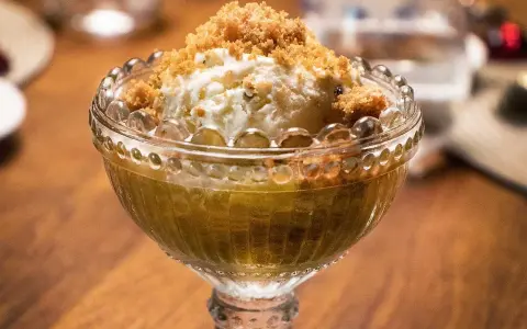 En skål med rabarberkompott och kardemumma, toppad med vaniljglass och smuldeg. En härlig dessert!
