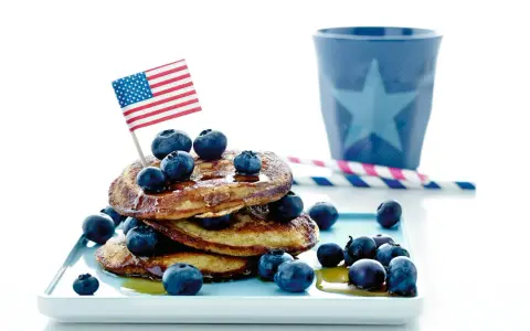 Amerikansk bananpannkaka recept med blåbär och en liten flagga. Perfekt för en festlig frukost!