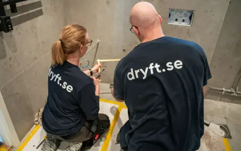 Två hantverkare från dryft.se mäter upp för att byta kommod i ett badrum.