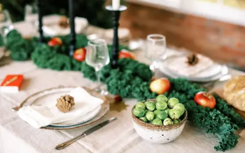 Vacker juldukning inspiration med grönt kale, äpplen och rosenkål. En rustik dukning som bjuder in till fest.
