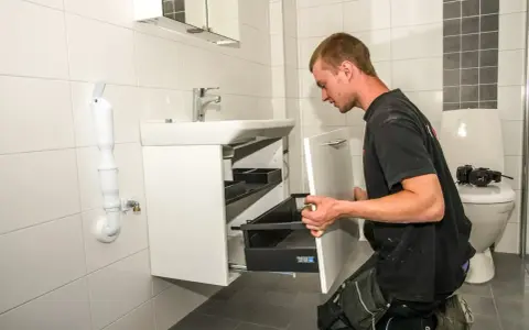 Hantverkare installerar ett nytt badrumsskåp som en del av en totalrenovering badrum.