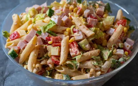 En stor skål med en härlig pastasallad med kassler, majs, tomat, gurka och en krämig dressing. Perfekt för sommaren!