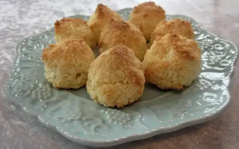 Små, gyllene kokostoppar på en vacker ljusblå tallrik. Perfekt för ett enkelt kokostoppar recept.