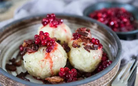 Tre runda pitepaltar toppade med lingon och knaperstekt fläsk. Ett klassiskt pitepalt recept som ser utsökt ut.