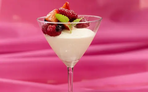 En elegant vit chokladmousse i ett martiniglas, toppad med färska bär och en myntakvist. En dröm för alla som älskar vit chokladmousse.