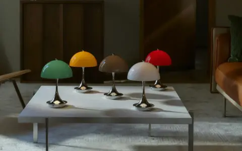 Fem färgglada lampor i Verner Panton-stil står på ett vitt bord framför en lädersoffa.