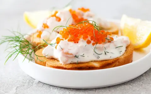 Toast Skagen med dill och rom på rostat bröd, garnerad med dillkvistar och citronklyftor.