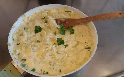 Krämig stuvad vitkål i en panna, garnerad med persilja. En klassisk svensk rätt som doftar hemtrevnad.