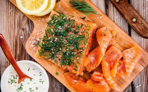 Njut av en bit gravad lax, toppad med dill och salt, serverad med citronskivor och en krämig sås.