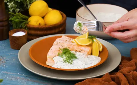 En gaffel med romsås till lax, serverad med citronklyftor och dill. En läcker och fräsch rätt.