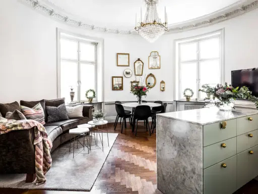 Ett vardagsrum med mörk soffa, marmorö, och en matplats. Massor av speglar på väggen ger inredning inspiration.