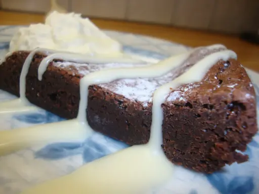 En bit chokladkaka med vispad grädde och vit chokladsås. En härlig vit kladdkaka som smälter i munnen.