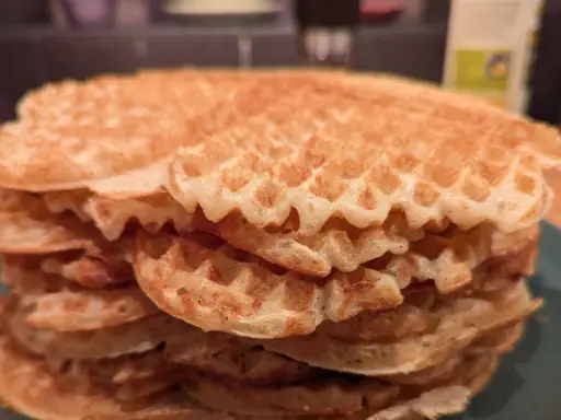 En hög med gyllene, glutenfria våfflor på en grön tallrik. Perfekt för en frukost eller fika!