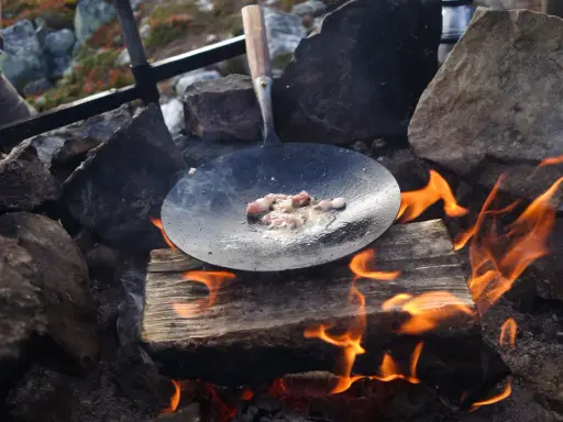 Stekt fläsk på en stekpanna över öppen eld, en del av ett kolbulle recept.