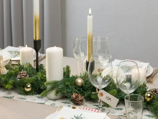 Vacker juldukning med granris, ljus och julgranskulor. En fin juldukning som skapar stämning.