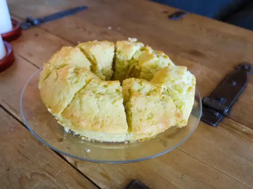 En saftig sockerkaka, uppskuren i bitar på ett fat, ligger på ett rustikt träbord.